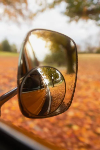 stock image A closeup of a side mirror of a car with the reflection of the autumn park