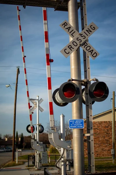 A vertical shot of rail crossing signal poles with lights and text \