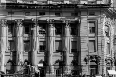 Gri tonda çekilen ayna pencerelerine yansıyan kolonları olan eski bir bina