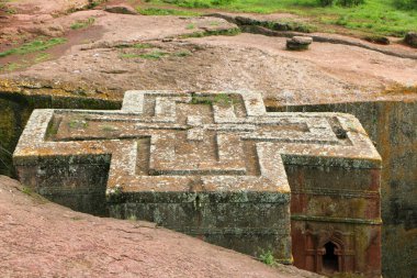 Aziz George 'un haç şeklinde taş yontulmuş kilisesi Lalibela, Etiyopya' da yeşil çimenler ve ağaçlarla çevrilidir.