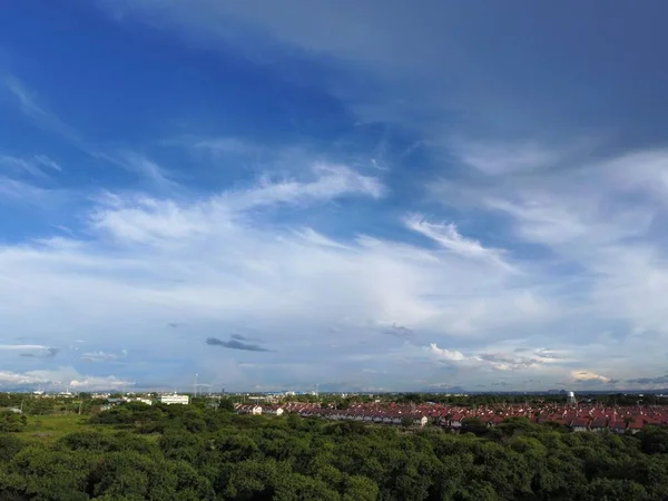 Mavili Bulutlu Gökyüzünün Altında Arka Planda Binalar Bulunan Yemyeşil Bir — Stok fotoğraf