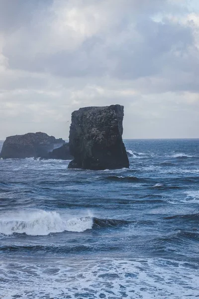 曇り空の前の海の岩の垂直方向の景色 — ストック写真