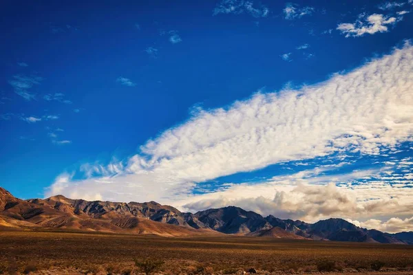 白い雲が浮かぶ青い空の下の丘と大規模なフィールドの風光明媚なショット — ストック写真