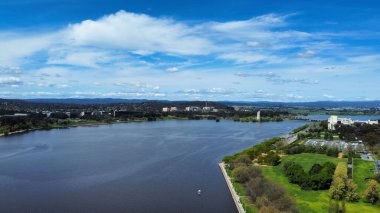 Mavi bulutlu gökyüzünün altındaki bir parkın yanındaki göle kuş bakışı bir bakış.