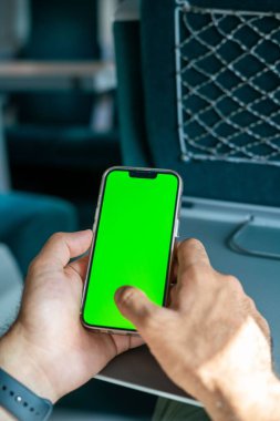 Kimliği belirsiz adam elinde yeşil ekranlı bir akıllı telefon tutuyor.,