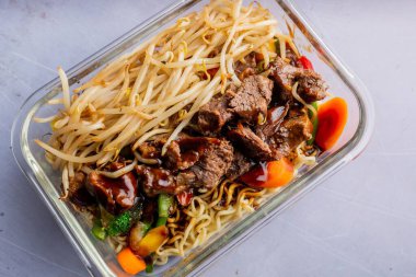 Lo mein tabağına yakın plan bir sos ve cam tabakta sebzeler.