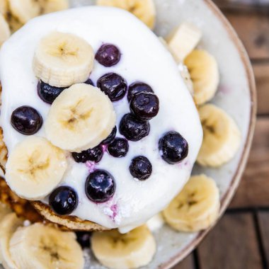 Muz dilimleri ve beyaz tabakta parlak yaban mersini manzarası.