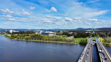 Parkın yakınındaki otoyollara ve mavi bulutlu gökyüzünün altındaki göle kuş bakışı bir bakış.