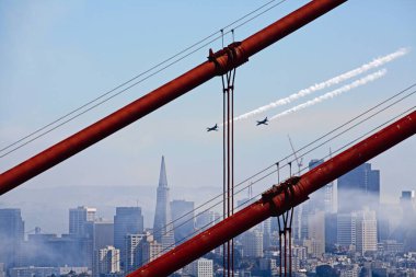 Golden Gate Köprüsü 'ndeki kırmızı metal kutuplar, mavi gökyüzünde uçan iki uçakla San Francisco.