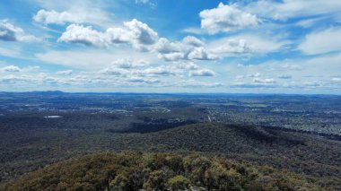 Orman tepeleriyle çevrili bir kasabanın kuş bakışı görüntüsü.