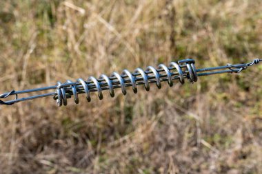 Metalik bir çadır yayı, kuru çimenlere yakın çekim.