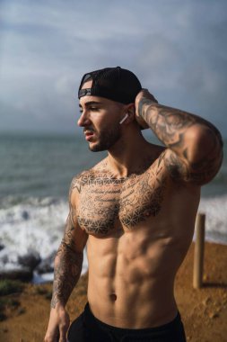 İspanya 'dan, plajda poz veren üstsüz, beyaz bir adam.