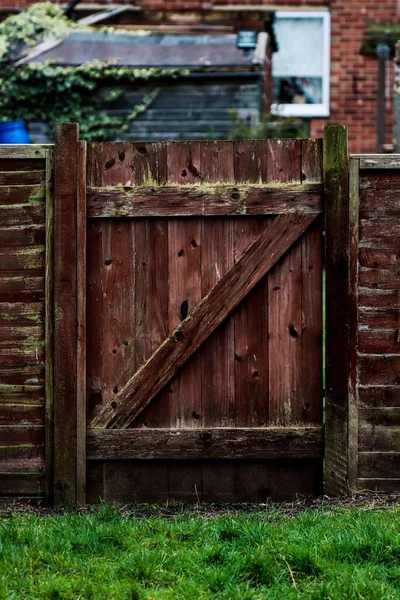 庭につながる古い木製の柵の門の垂直ショット — ストック写真