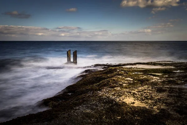 Δύο Ξύλινες Κολόνες Που Προεξέχουν Από Τον Ωκεανό Και Αιχμαλωτίζονται — Φωτογραφία Αρχείου
