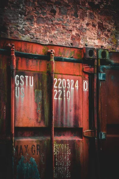技術的な特性のテキストと古い赤い錆びた船積みコンテナドアの垂直ショット — ストック写真