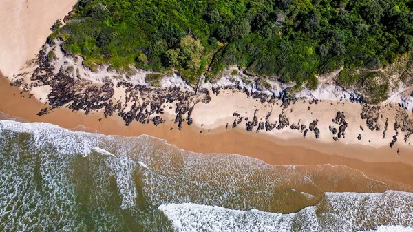 stock image An aerial view of sea waves breaking greenery beach