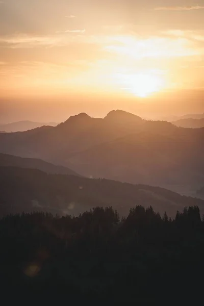 丘や木のシルエットの上の穏やかな空の美しい夕日の風景 — ストック写真
