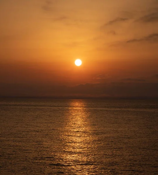 Vertikální Záběr Zářícího Západu Slunce Nad Klidným Mořem Temného Večera — Stock fotografie