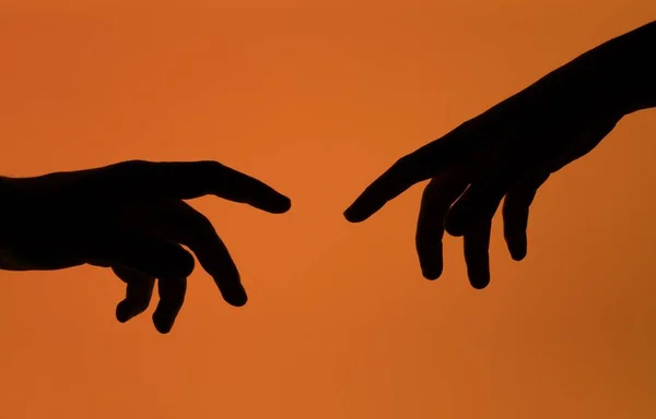 Silhouette Shot Two Hands Reaching Each Other Isolated Orange Background — Stock Photo, Image