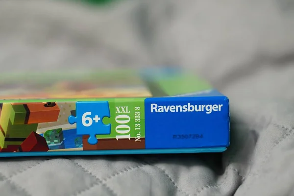 Ravensburger ブランドのMinecraftパズルが 背景がぼやけたベッドの上で閉じられました — ストック写真