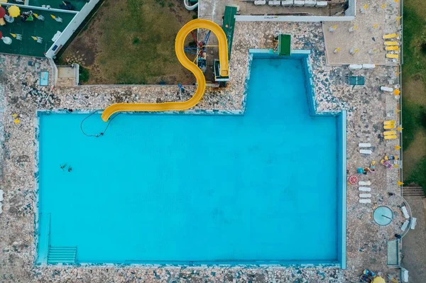 一个自上而下的无人驾驶飞机拍摄的带有大黄色滑梯的室外游泳池 — 图库照片