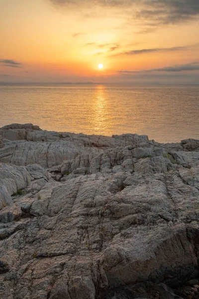 岩の崖の垂直ショットと海の夕日の反射 — ストック写真