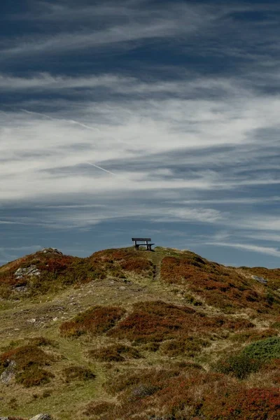 曇った空の背景にオーストリアの地平線の丘の上に面した孤独な木製のベンチ — ストック写真
