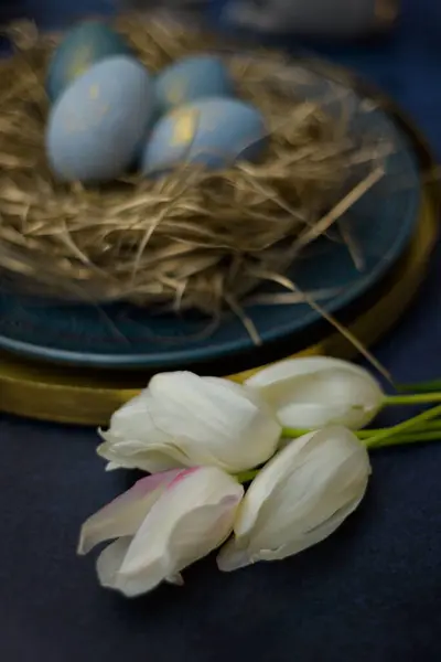 Вертикальный Снимок Белых Цветов Тюльпана Возле Гнезда Голубыми Декоративными Яйцами — стоковое фото