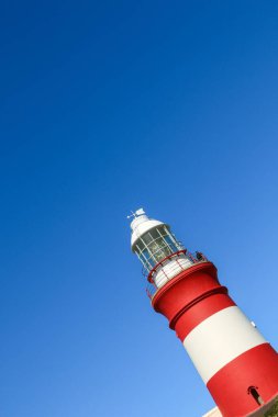 Güney Afrika, Agulhas Burnu 'ndaki kırmızı ve beyaz deniz fenerinin dikey alçak açılı görüntüsü.