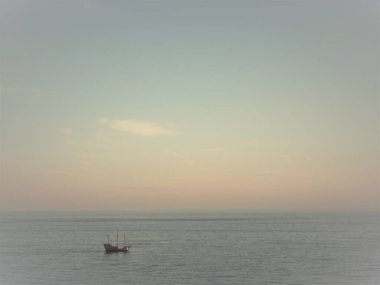 Gün batımında okyanusta tek başına güzel bir tekne görüntüsü.