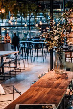 Çiçek vazosuyla boş bir restoran masasının dikey görüntüsü.