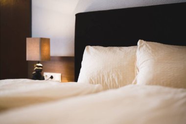 Otel odasındaki yatağın yanında bir lamba.