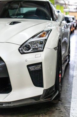 Park yerindeki beyaz Nissan GT-R spor arabasının dikey görüntüsü.