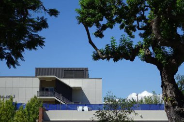 Güneşli bir günde yeşil ağaçlarla çevrili merdivenleri olan modern bir bina.