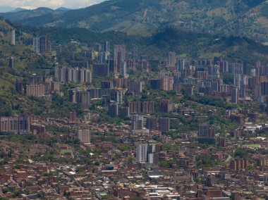 Güneşli bir günde yüksek binalar ve yeşil doğa ile Medellin şehrinin havadan görünüşü.