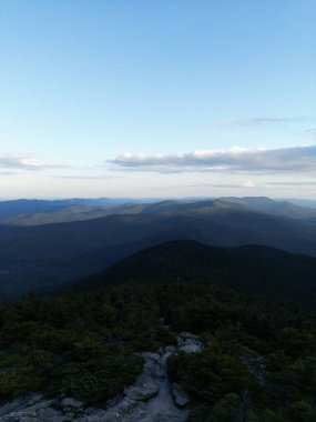 Bulutlu mavi gökyüzünün altındaki dağ tarlalarının dikey görüntüsü.