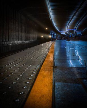 Metro istasyonuna karanlık tonlarda gelen bir trenin dikey çekimi.