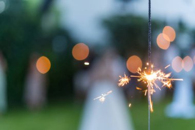 Açık havada yanan bir havai fişek bulanık arka planda parlayan bengal ışıkları