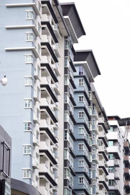 Kuala Lumpur 'daki yüksek katlı mavi bir binanın dikey görüntüsü.