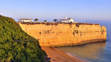 Mavi gökyüzüne karşı beyaz binaları olan güzel kayalık deniz kıyısı.