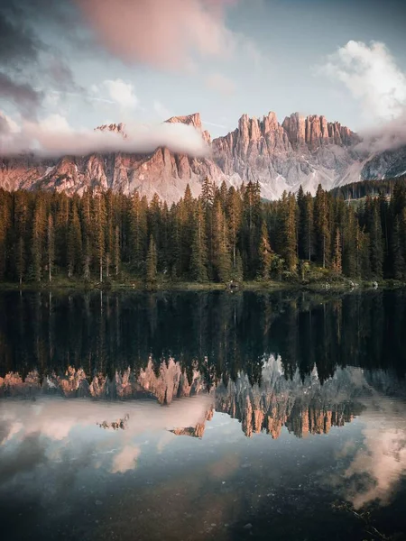 日の出の間に森とイタリアのドロマイトに囲まれた湖の垂直ショット — ストック写真