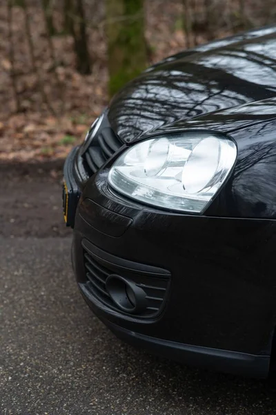 Eine Vertikale Aufnahme Des Scheinwerfers Eines Schwarzen Autos Auf Einer — Stockfoto