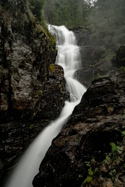在布满苔藓的岩石湿悬崖之间长时间地暴露在瀑布中 — 图库照片