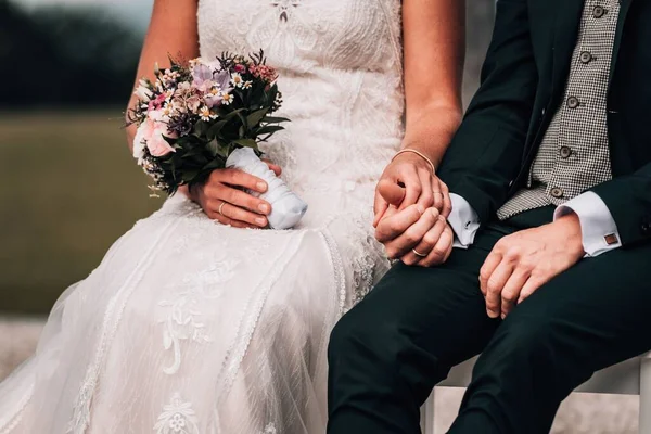 ベンチで手をつないで座っている新婚夫婦のクローズアップショット — ストック写真