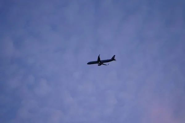 雲に覆われた青空の下を飛行する飛行機の低角度ショット — ストック写真