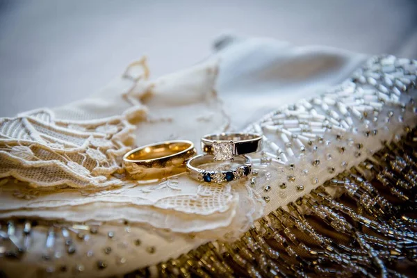 Svatební Prsteny Krémové Tkanině Zdobené Skleněnými Perlemi Rozmazaném Pozadí — Stock fotografie