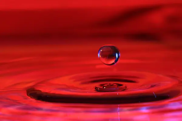 Капля Воды Брызгающаяся Поверхность Воды Освещенной Красным Светом — стоковое фото