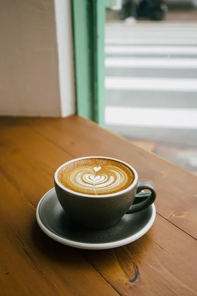 コーヒーショップのテーブルの上に灰色のカップのコーヒーの垂直ショット — ストック写真