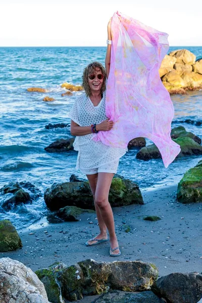 stock image A vertical of Hispanic female model over 50 years with pink scarf and sunglasses on the beach