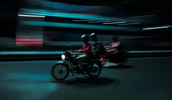 夜間にヘルメットを頭に2台のバイクに乗っている3人の横顔のぼやけたショット — ストック写真